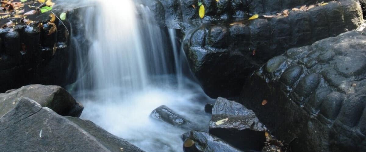 A waterfall flowing over dark rocks with carvings.
