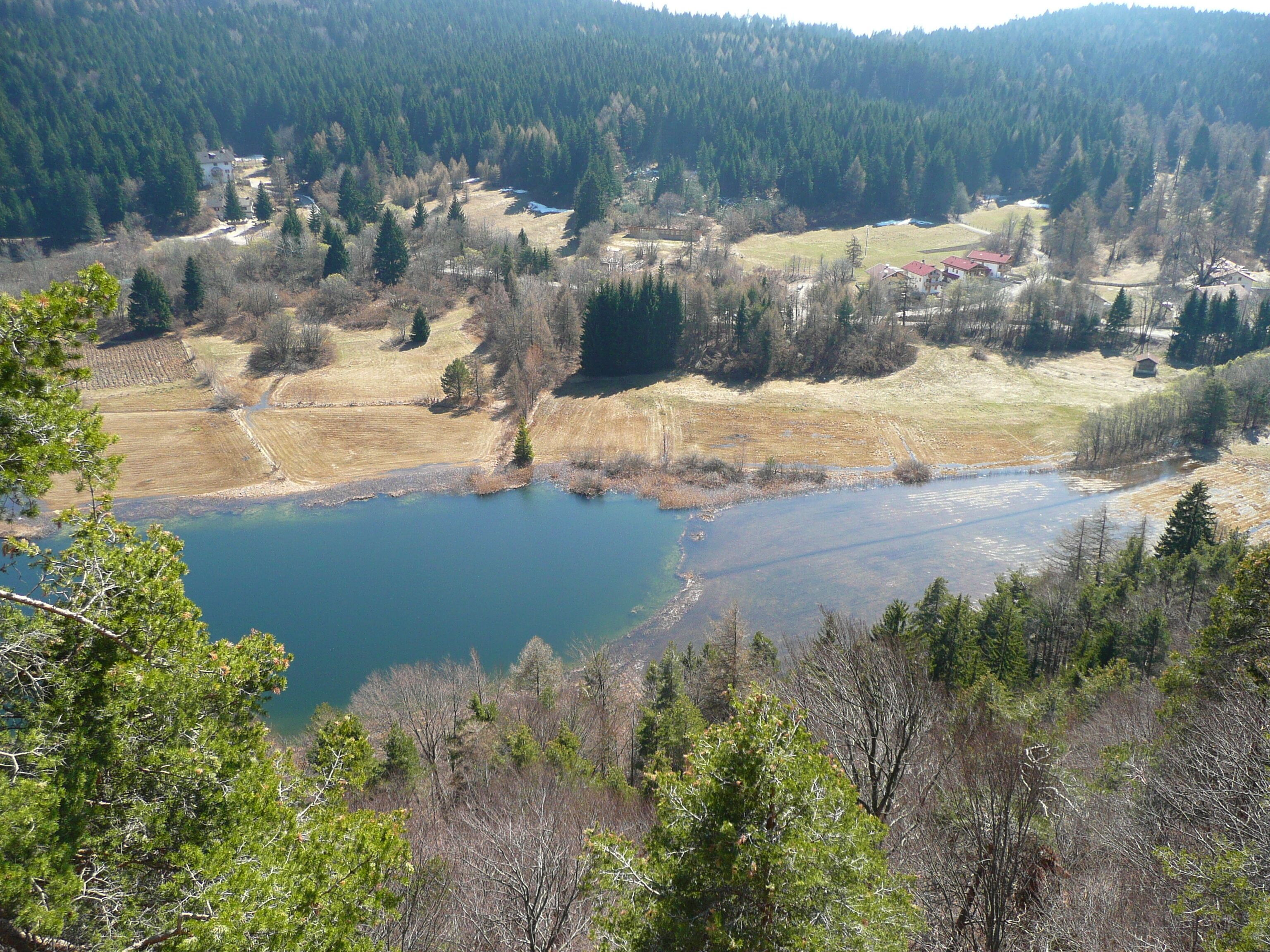 A lake surrounded by forested hills and scattered buildings.