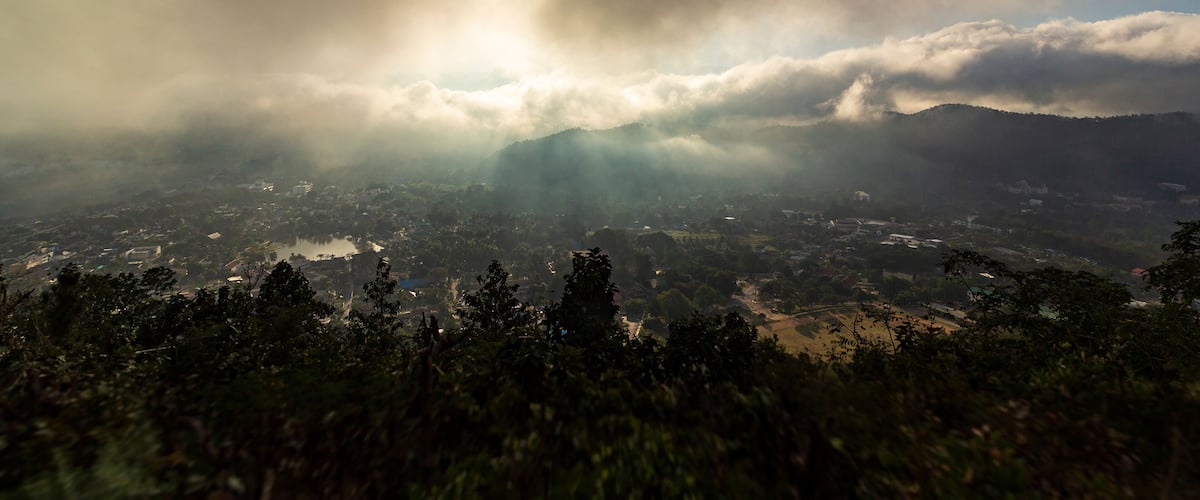 A mountainous landscape with a valley, dense forest, and a river.