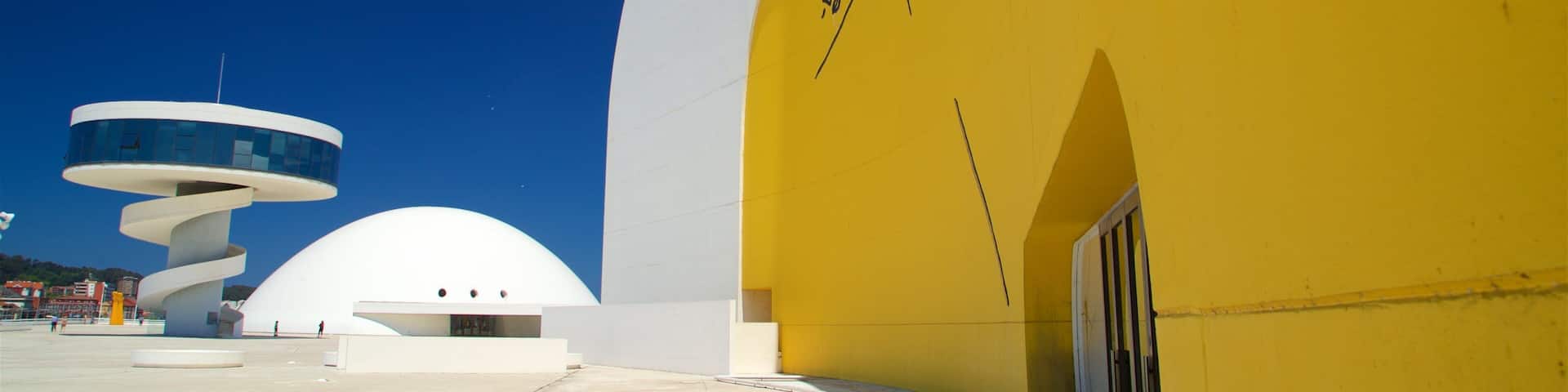 A modern building with a yellow facade and a white dome structure.