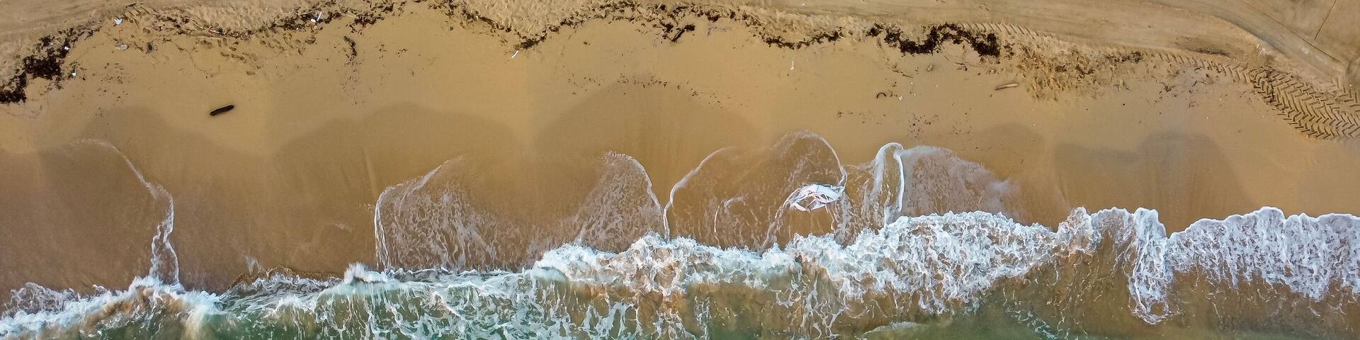 Top down view beach and mediterranean sea with waves. Aerial view abstract coastline in summer. Marina di Ostui, Puglia, Italy