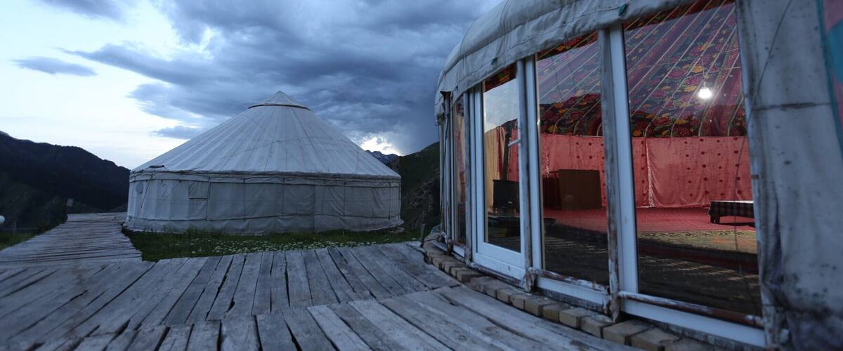 A yurt with a wooden deck and a large glass window.