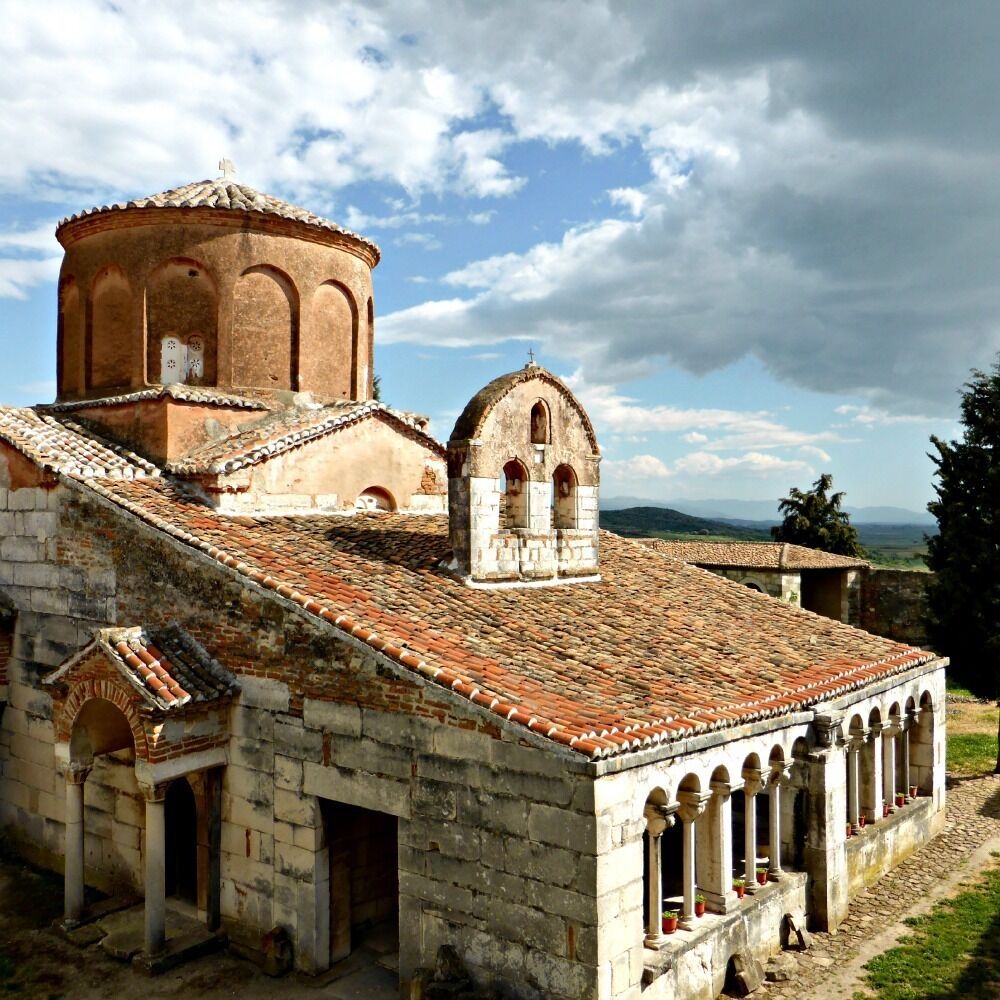 An ancient stone building with a tiled roof and arched windows.