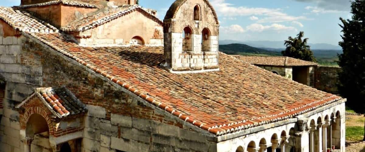 An ancient stone building with a tiled roof and arched windows.