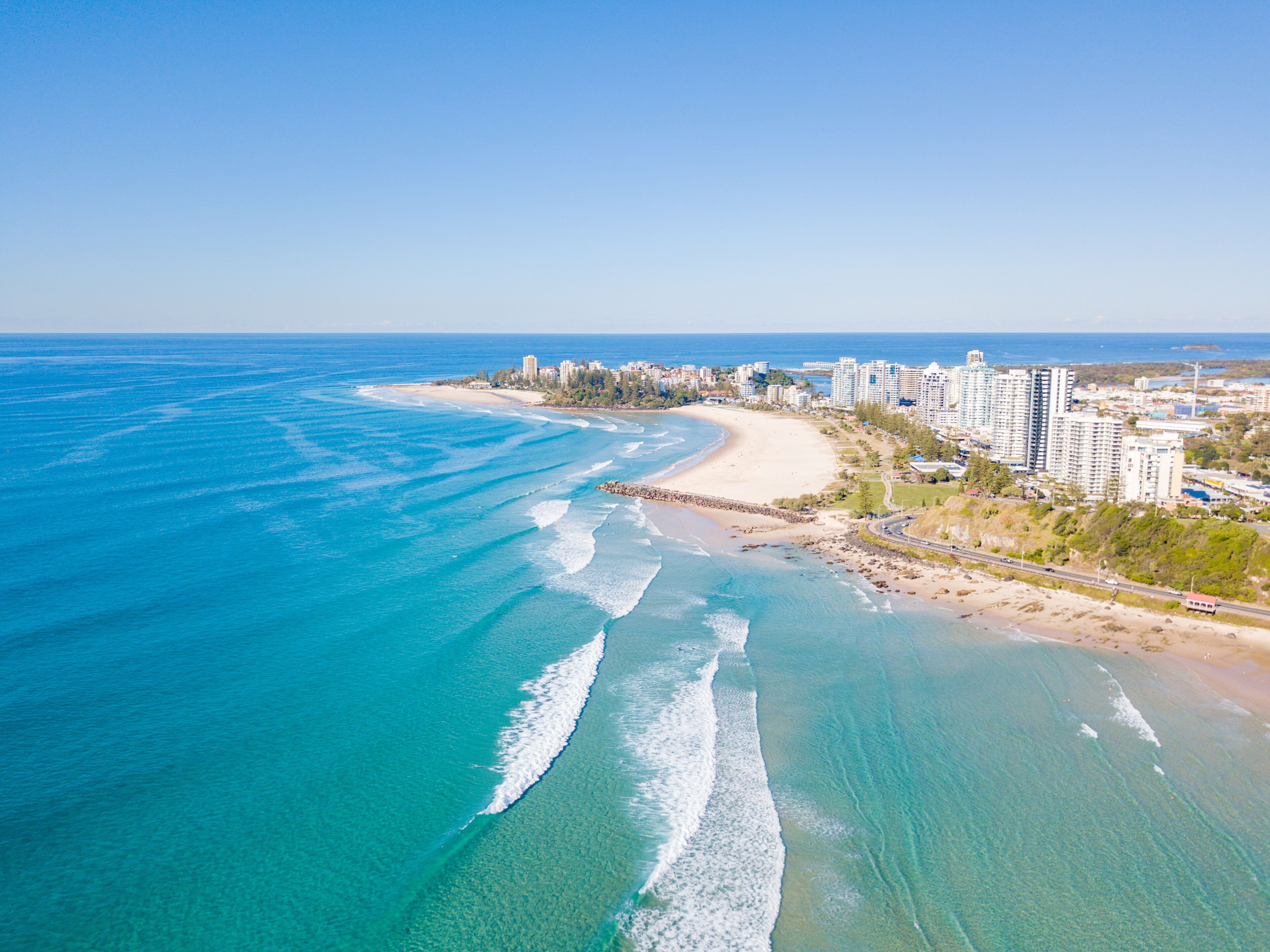 A coastal city with a beach, ocean waves, and high-rise buildings.