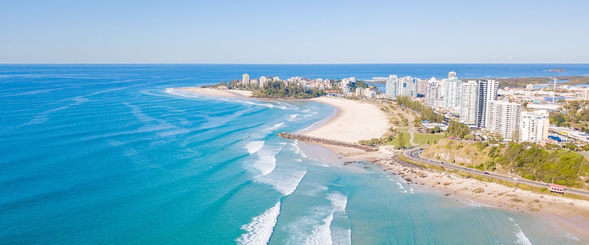 A coastal city with a beach, ocean waves, and high-rise buildings.