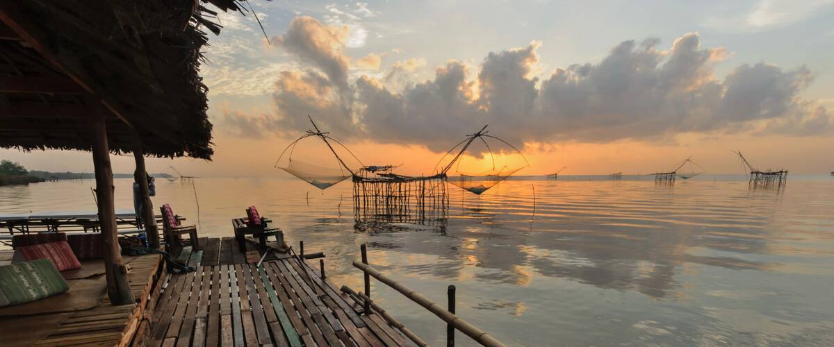 A wooden pier with fishing nets and a thatched roof structure.