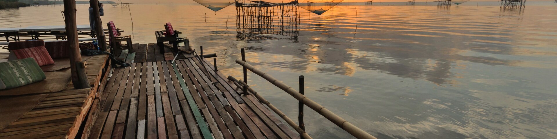 A wooden pier with fishing nets and a thatched roof structure.