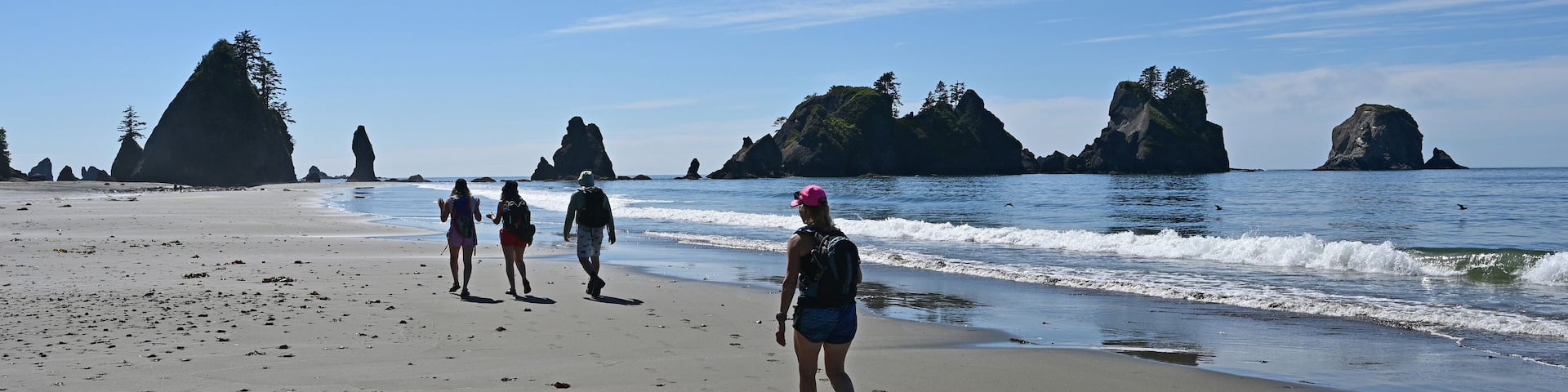 Hikers on Shi Shi Beach Trail in Olympic National Park near Neah Bay, Washington on sunny summer afternoon with Point of Arches in background.