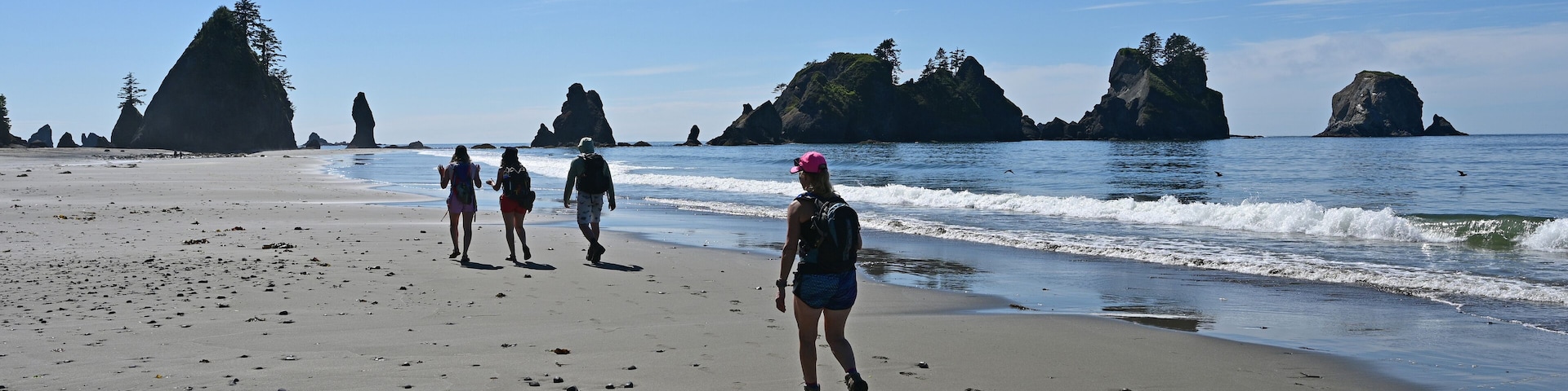 Hikers on Shi Shi Beach Trail in Olympic National Park near Neah Bay, Washington on sunny summer afternoon with Point of Arches in background.