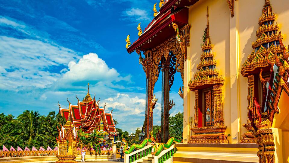 A traditional Thai temple with ornate architecture, including golden spires and intricate designs.