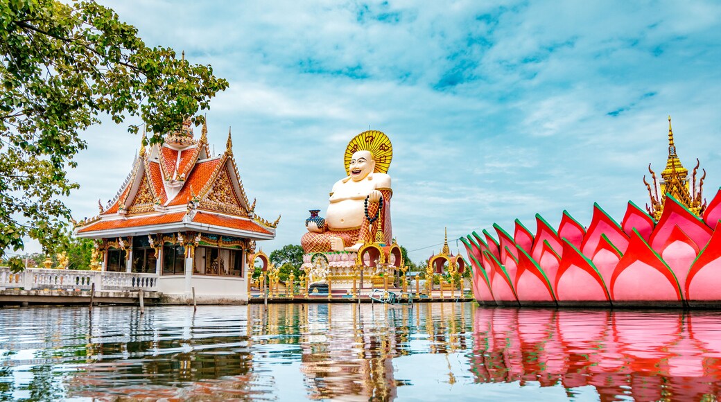 Wat Plai Laem Buddhism Temple statues during a bright sunny day with lake in the foreground in Koh Samui, Surat Thani, Thailand