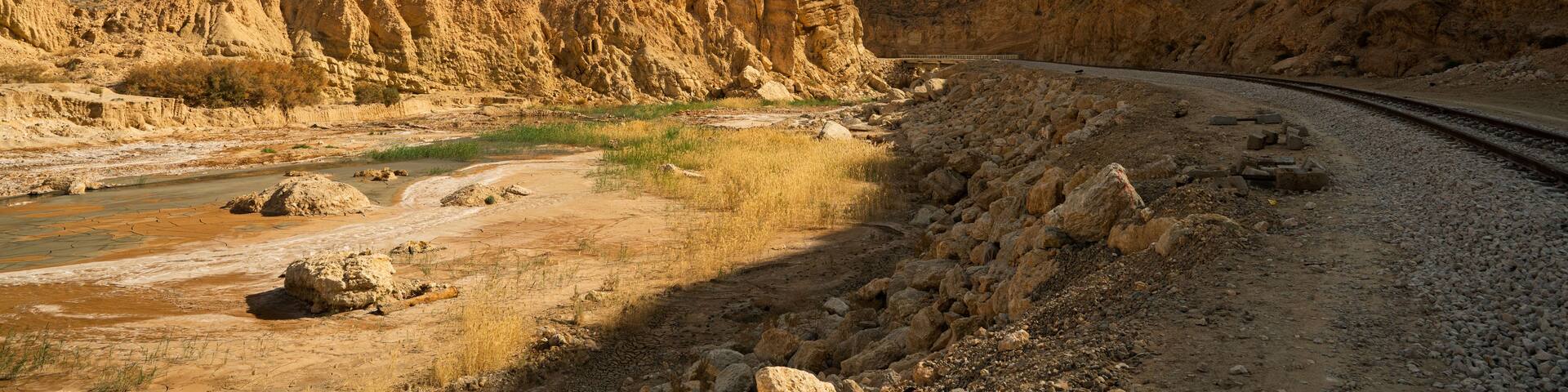 A desert landscape with a winding road, rocky terrain, and a prominent hill.