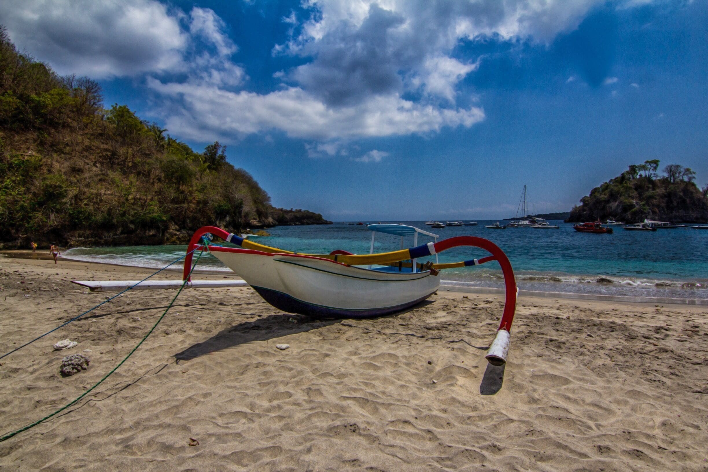 A boat on a sandy beach with a clear blue sky and calm sea.