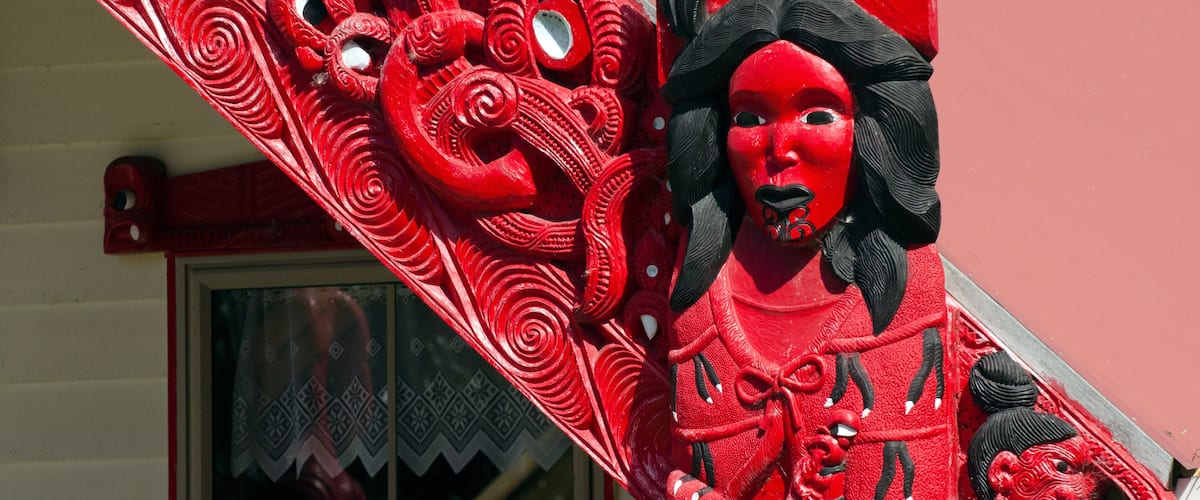 A red and black statue with intricate designs on a building facade.