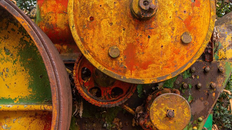 A rusted mechanical part with a chain and bolts.
