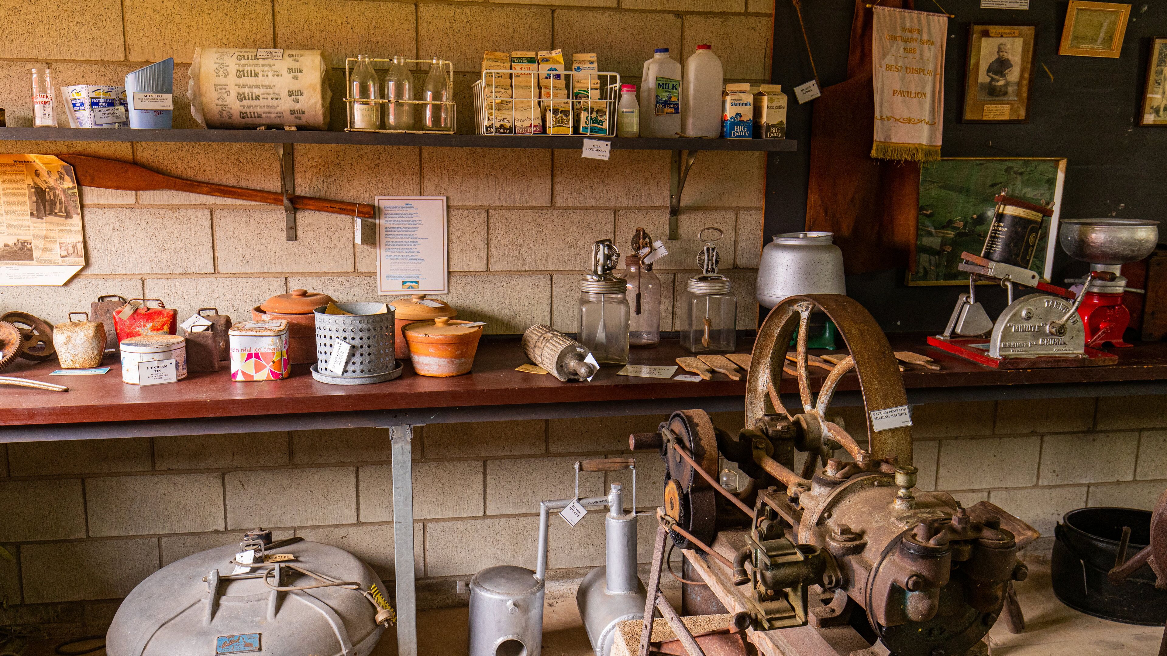Una exhibición antigua de productos lácteos con botellas de leche, cartones y equipo lechero antiguo.