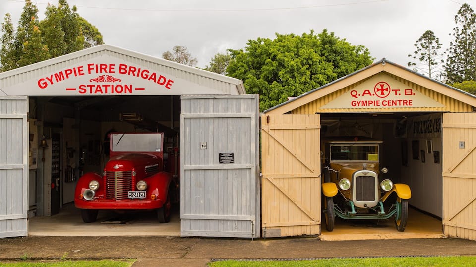 A vintage red fire engine and a classic motorcycle at the Gympie Fire Brigade Station and Gympie Centre.