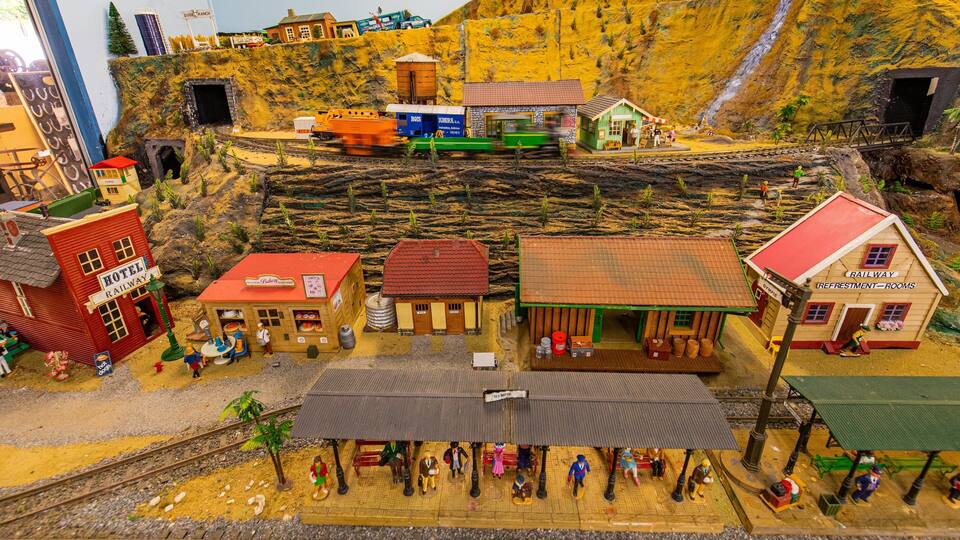 A detailed model train set with miniature buildings, a train, and a rocky landscape.