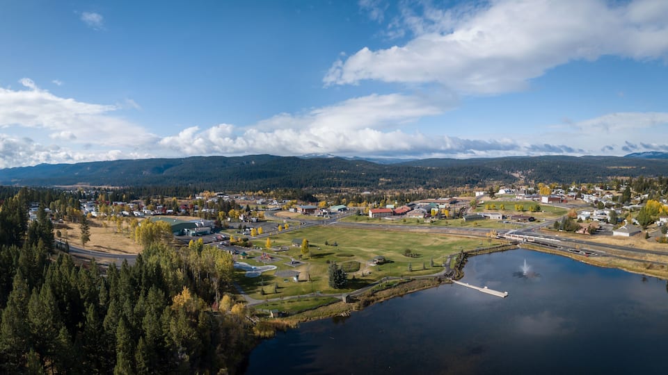 A lakeside town with a bridge, a marina, and mountains in the background.