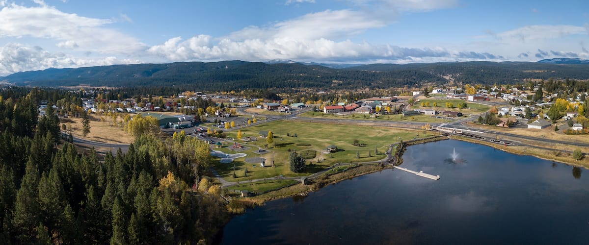 A lakeside town with a bridge, a marina, and mountains in the background.