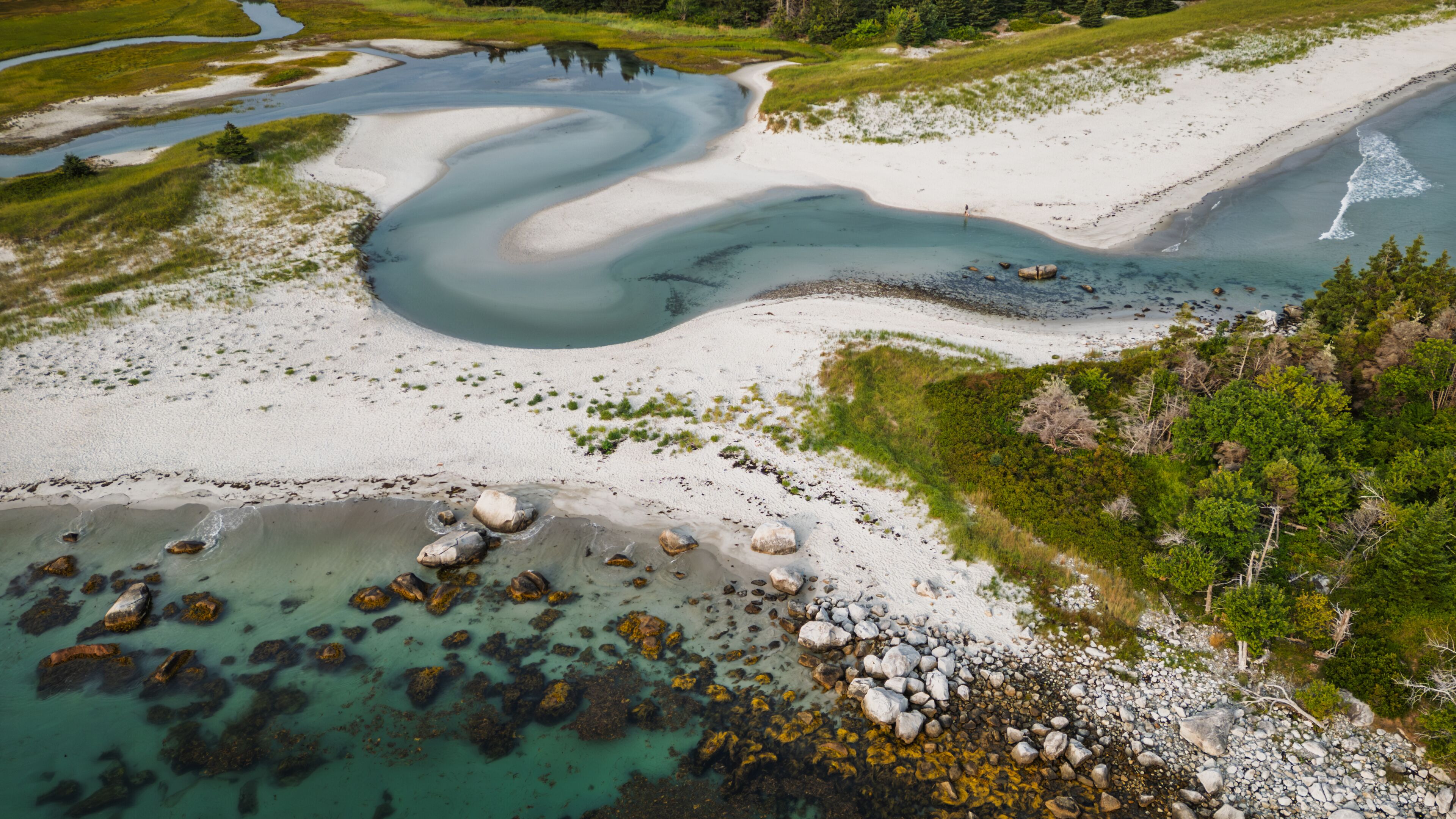 A river winding through a sandy landscape with rocky outcrops and dense greenery.