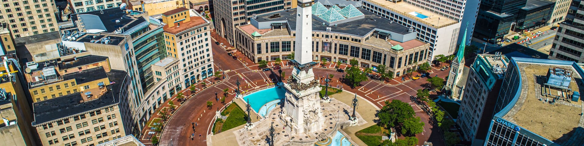 A cityscape with a central plaza featuring a fountain, surrounded by high-rise buildings.