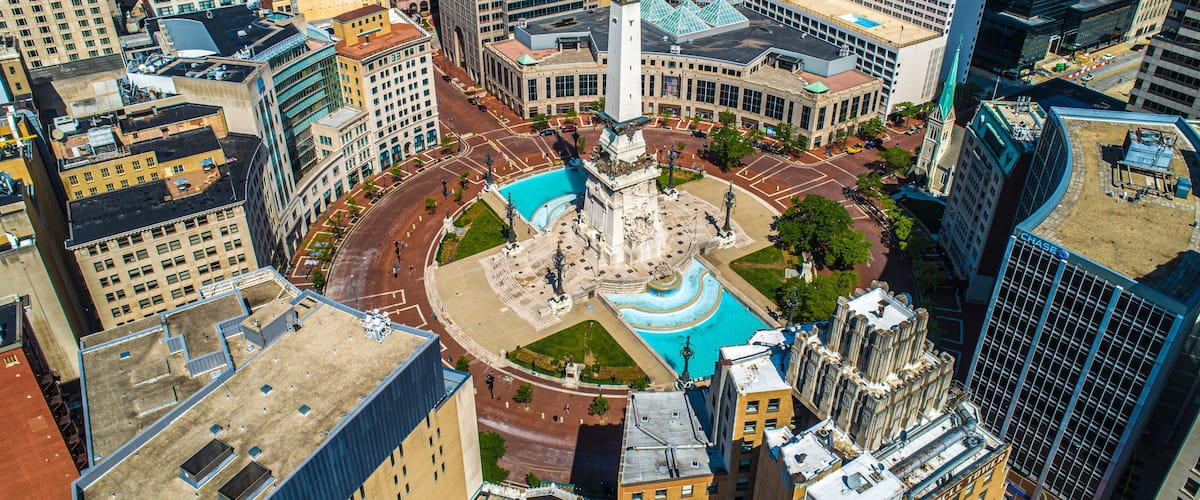 A cityscape with a central plaza featuring a fountain, surrounded by high-rise buildings.