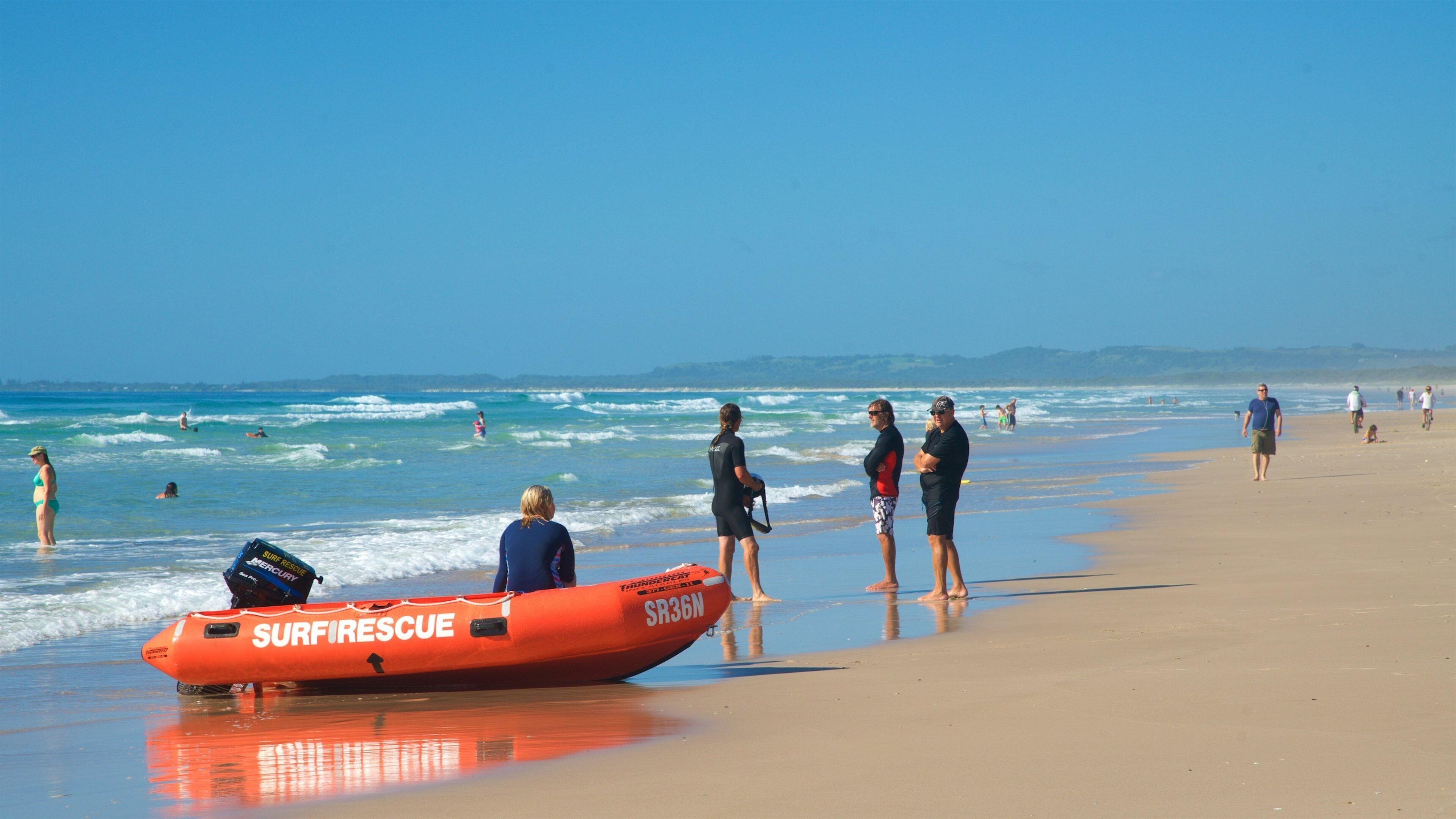 A beach with a surf rescue boat, people walking, and waves.