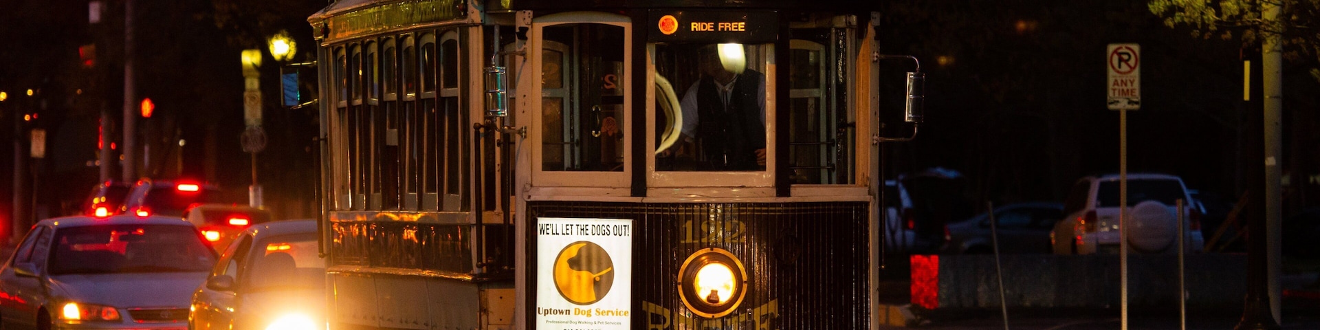 Un tranvía antiguo con un cartel que dice 'Viaje Gratis' y otro anuncio que promociona el servicio Uptown Dog.