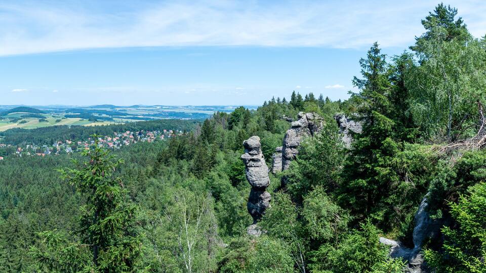A mountainous landscape with dense forests, a village, and distinctive rock formations.