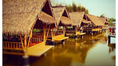 Cabañas sobre el agua con techos de paja y construidas sobre pilotes, sobre aguas tranquilas.