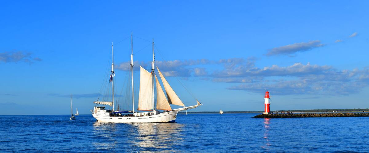 A sailboat on the water with a lighthouse in the background.