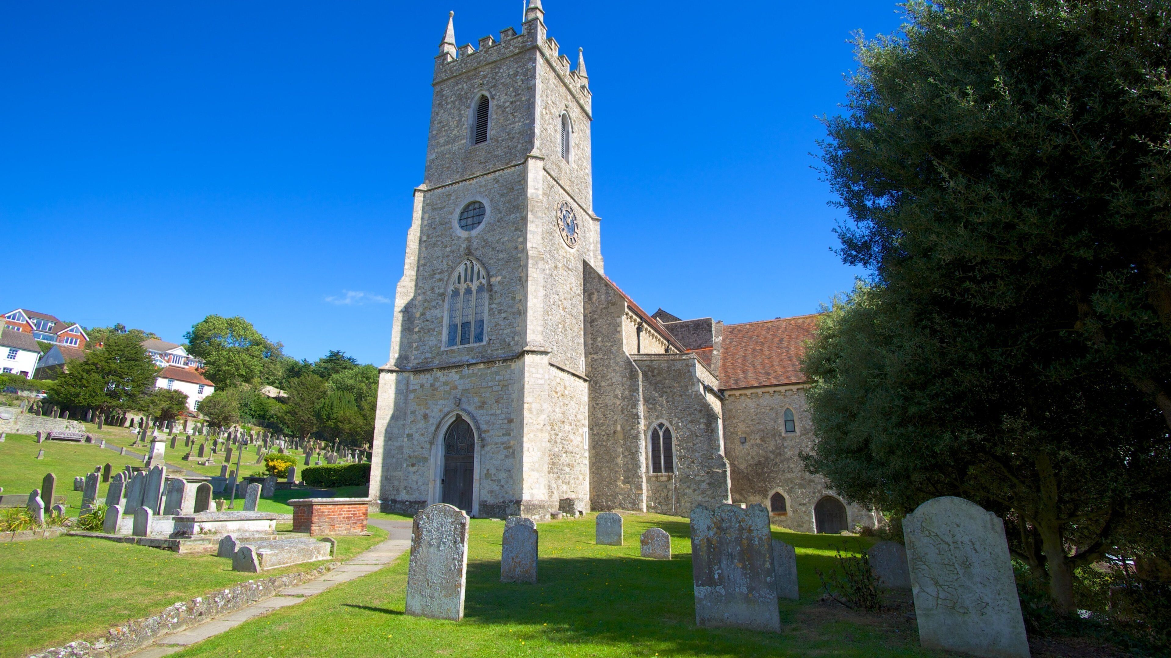 A church with a tall tower and a cemetery in the foreground.