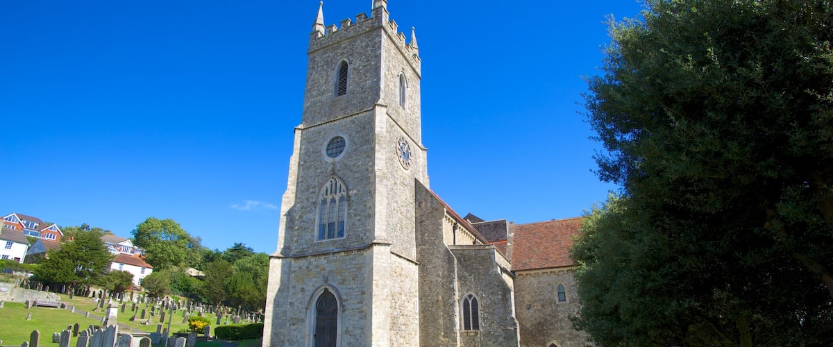 A church with a tall tower and a cemetery in the foreground.