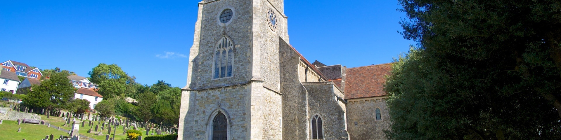 A church with a tall tower and a cemetery in the foreground.