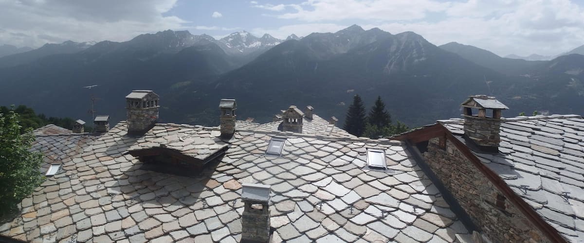 A mountainous landscape with stone-roofed buildings and a clear sky.