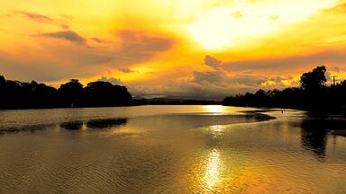 Brilliant golden sunlight of a late afternoon highlights the cloud formations and creates beautiful reflections in the calm waters of a coastal river, Mylestom ,NSW ,Australia.