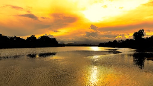 Brilliant golden sunlight of a late afternoon highlights the cloud formations and creates beautiful reflections in the calm waters of a coastal river, Mylestom ,NSW ,Australia.