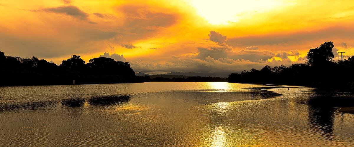 A sunset over a calm river with reflections of the sky.