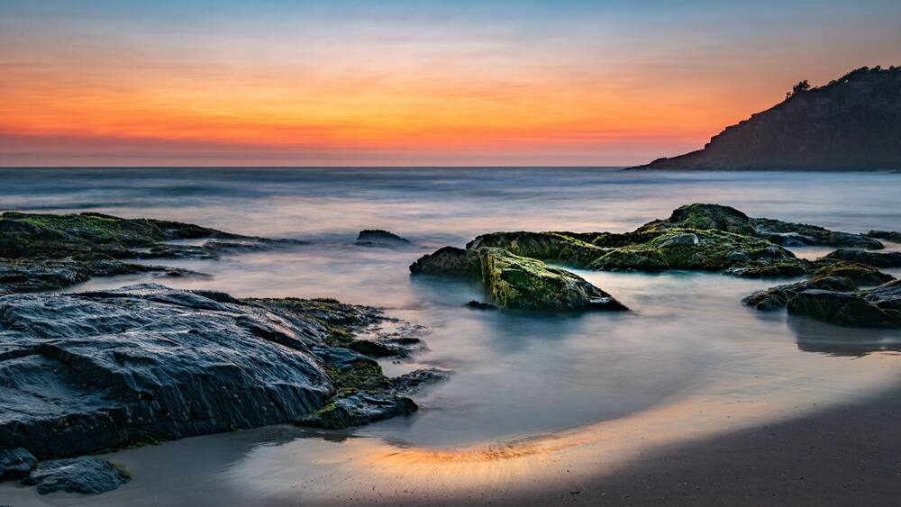 Smoke on the water fire in the sky - bushfire smoke haze creating beautiful warm muted tones during sunrise at the beach.