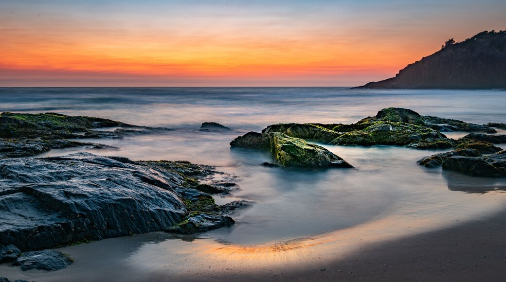Smoke on the water fire in the sky - bushfire smoke haze creating beautiful warm muted tones during sunrise at the beach.