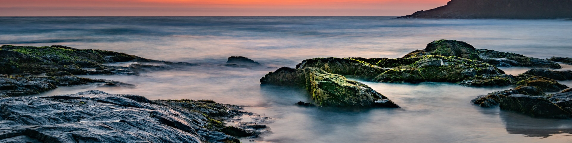 Smoke on the water fire in the sky - bushfire smoke haze creating beautiful warm muted tones during sunrise at the beach.
