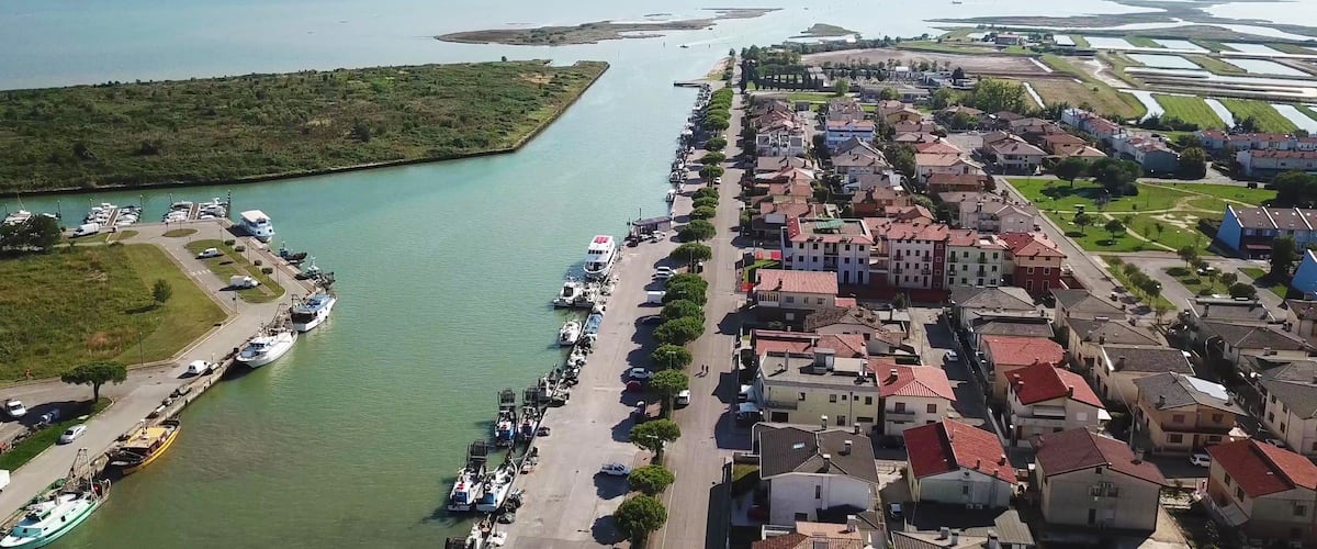 An aerial view of a coastal town with a marina, residential buildings, and a large body of water.