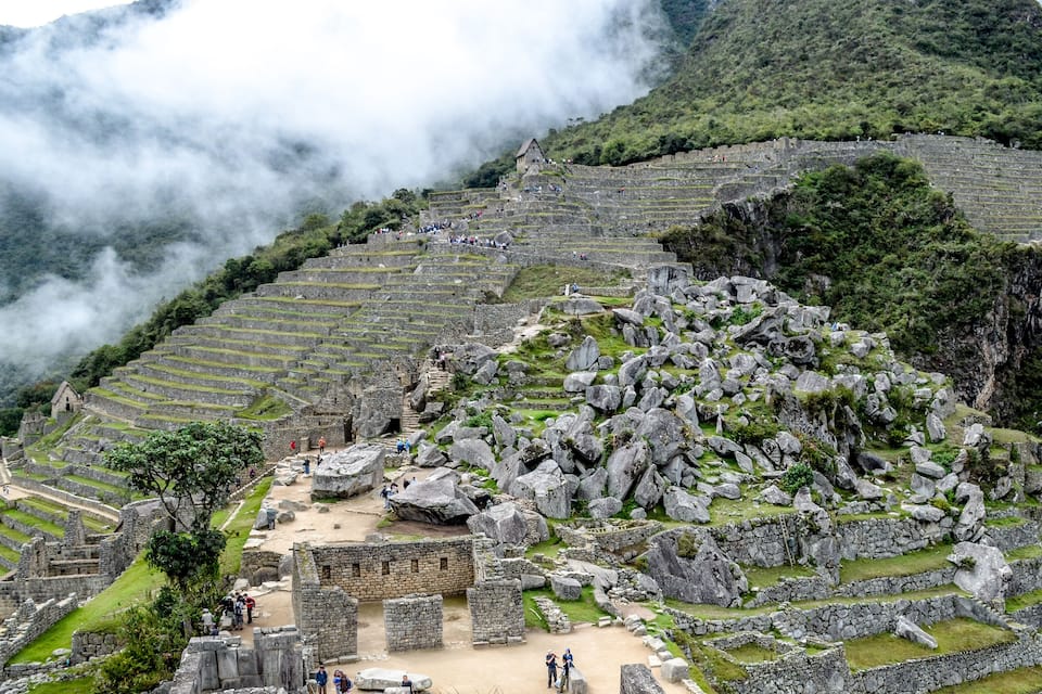 Ruínas de Machu Picchu com campos em socalcos e montanhas ao fundo.