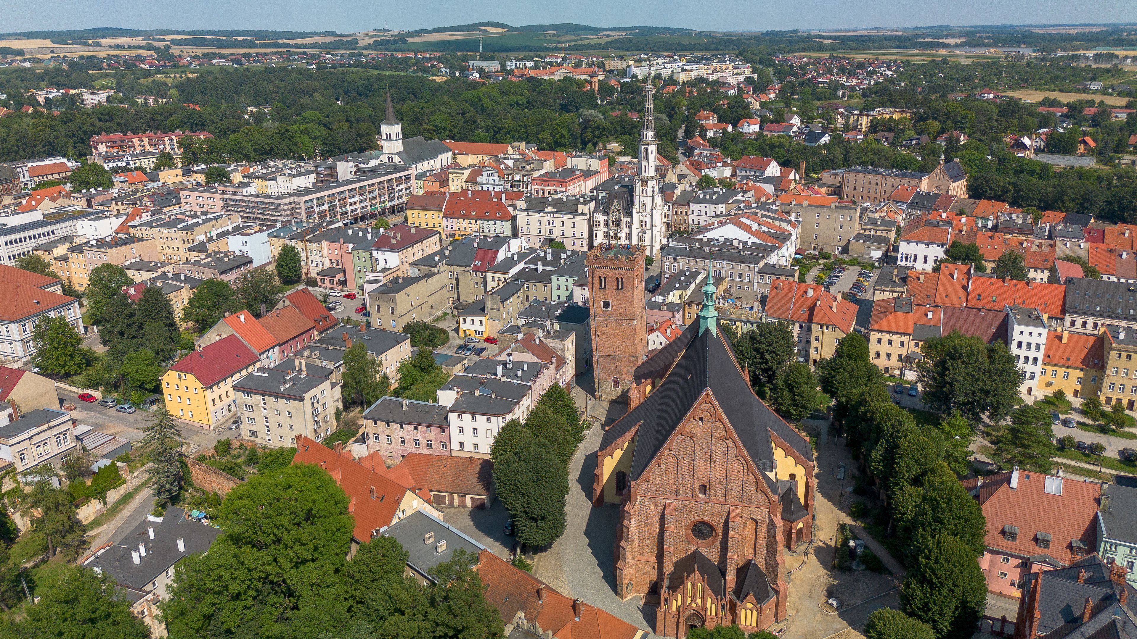 A cityscape with a prominent church featuring a tall spire and a clock tower, surrounded by residential buildings and greenery.