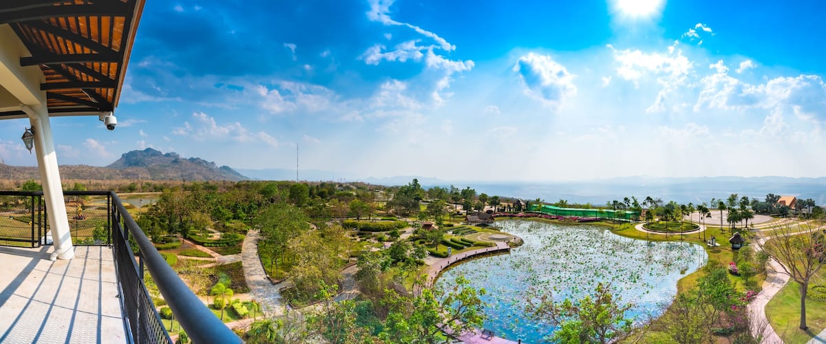 A scenic view of a park with a pond, pathways, and distant mountains.