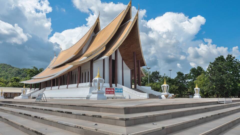 A traditional Thai temple with tiered roofs and a staircase leading up to the entrance.