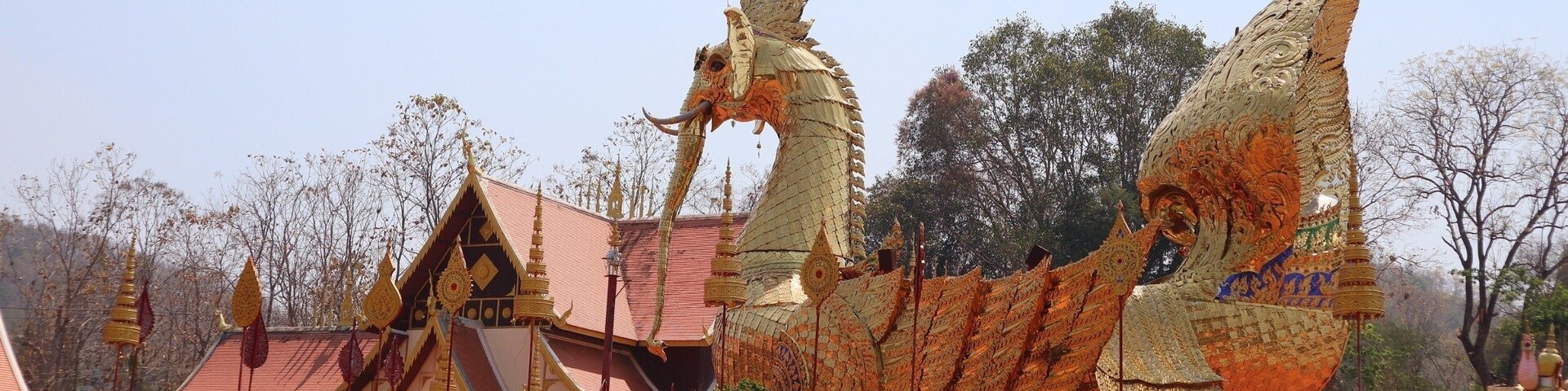 Un templo tailandés tradicional con decoraciones elaboradas y una gran escultura de dragón.