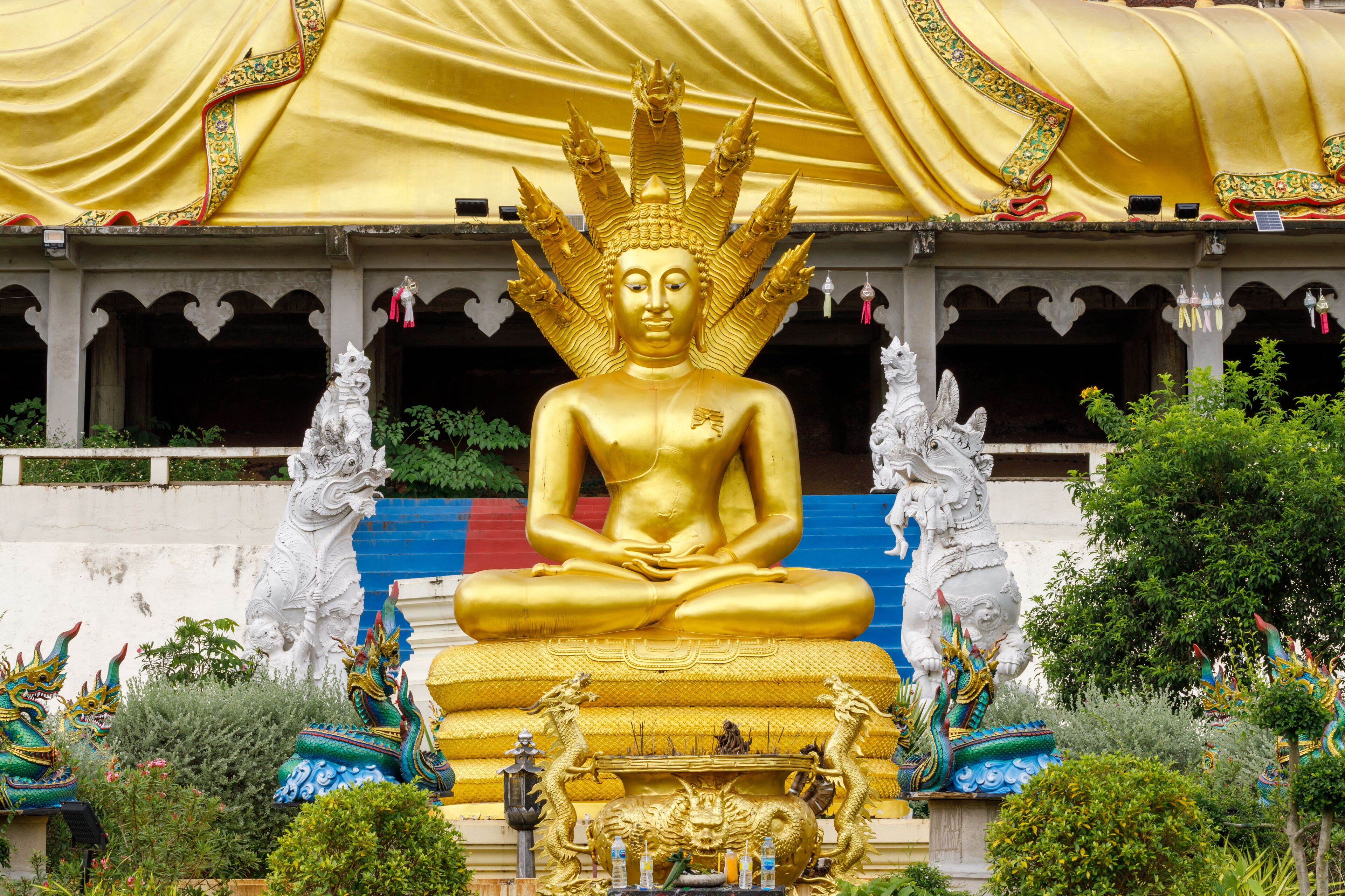 A large golden Buddha statue with a multi-tiered crown, surrounded by smaller statues and colorful dragons.